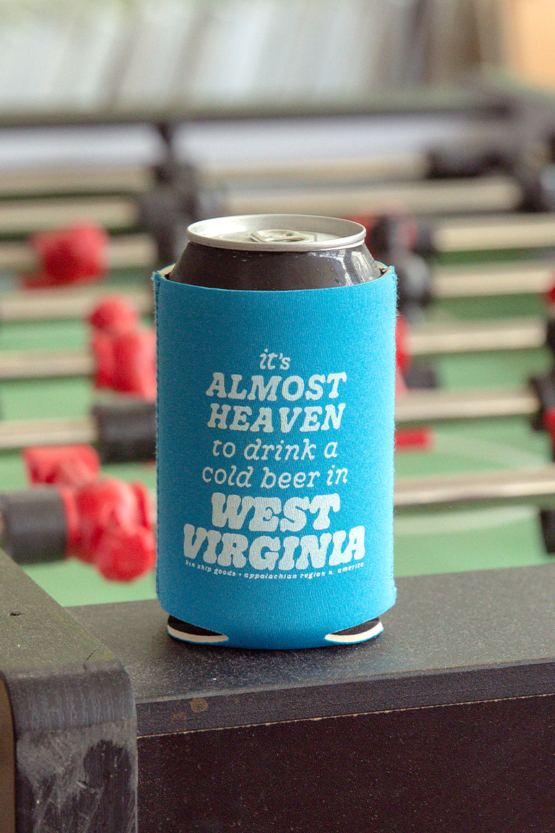 Kin Ship Goods bright blue koozie with “It’s almost heaven to drink a cold beer in West Virginia” printed in white text.

