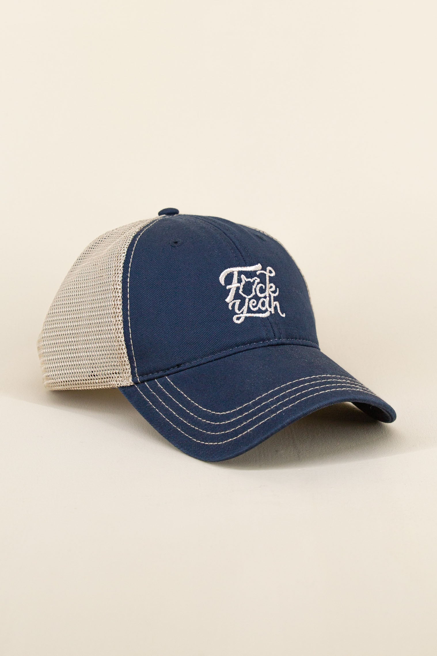 Navy Kin Ship Goods hat with tan mesh back and white embroidered ‘F*ck Yeah’ text with West Virginia outline, angled on neutral background.