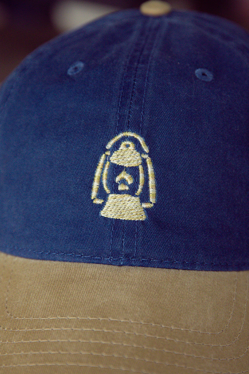 Kin Ship Goods lantern hat with navy crown and khaki brim—embroidered Appalachian lantern logo on classic cotton dad cap.